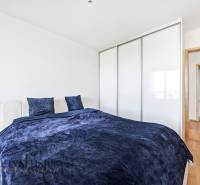 Schlafzimmer in einer 2-Zimmer-Wohnung mit Bett, Kleiderschrank und Boden in Holzoptik.