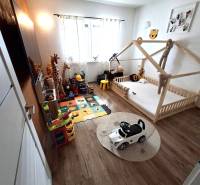 Kinderzimmer im Einfamilienhaus mit Kinderbett, Spielzeug und Boden in Holzoptik.