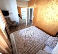 Ein Schlafzimmer in einem Einfamilienhaus mit Holzboden, braunen Vorhängen und einem gemusterten Bett.