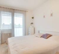 Schlafzimmer in einer 3-Zimmer-Wohnung mit einem hellen Bett und einer Kommode, dekoriert mit einer Pflanze.