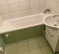 Badezimmer mit Badewanne und Waschbecken in einer 3-Zimmer-Wohnung mit hellen Fliesen und Verkleidungen.