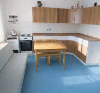 Eine Küche in einem Einfamilienhaus mit blauem Teppich und Holzschränken.