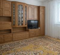 Wohnzimmer in einem Einfamilienhaus mit einer Wohnwand aus Holz und einem gemusterten Teppich.