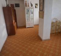 Innenraum eines Einfamilienhauses mit Vitrine und Teppichboden, Dekorationen und Bildern an den Wänden.