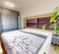 Schlafzimmer in einer 3-Zimmer-Wohnung mit Holzboden, großem Bett und Pflanze.