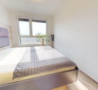 Schlafzimmer in einer 3-Zimmer-Wohnung mit großem Fenster, Bett und Boden mit Holzdekor.