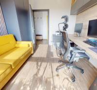 Ein Arbeitszimmer in einer 3-Zimmer-Wohnung mit Holzboden und einem gelben Sofa.