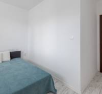 Schlafzimmer in einer 2-Zimmer-Wohnung mit Bett, Kissen und Holztüren.