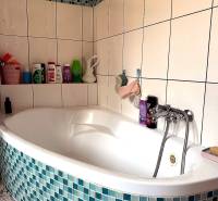 Badezimmer mit Eckbadewanne und blau-weißen Fliesen in einer 2-Zimmer-Wohnung.