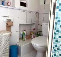 Badezimmer in einer 2-Zimmer-Wohnung mit weißen Fliesen, Stauraum und Toilette.