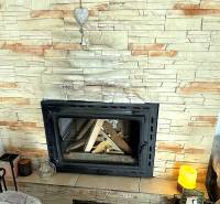 Kamin in einer 2-Zimmer-Wohnung mit Verkleidung aus Kunststein und dekorativem Herz.