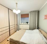 Schlafzimmer mit Bett, Einbauschrank und Boden mit Holzdekor in einer 3-Zimmer-Wohnung.