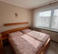 Schlafzimmer in einer 3-Zimmer-Wohnung mit Holzmöbeln und einem Boden in Holzoptik.