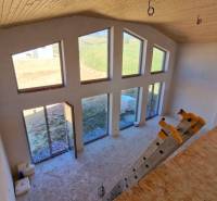 Das Innere der Hütte mit großen Fenstern, Treppenstufen und einem Boden mit Holzdekor.