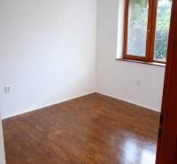 Ein Zimmer mit Holzelementen, weißen Wänden, einem Fenster, ohne Möbel in einer 3-Zimmer-Wohnung.