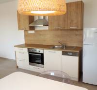 Küche in einem Studio-Apartment in der Bodona-Straße mit Holzschränken, Herd und Kühlschrank.