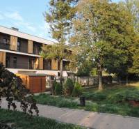 Das Wohnhaus in der Bodona-Straße, umgeben von Grünflächen und Bäumen, ideal für das Wohnen in einer Einzimmerwohnung.