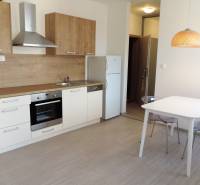 Küche in einem Studio-Apartment auf Bodona, Einfachheit mit Esstisch und grauen Stühlen.