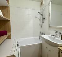 Badezimmer in einer 3-Zimmer-Wohnung mit Badewanne, Waschbecken und Regalspeicherplatz.