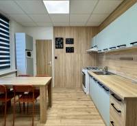 Küche in einer 3-Zimmer-Wohnung mit Esstisch und Boden mit Holzdekor.