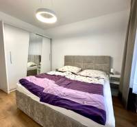 Schlafzimmer in einer Zweizimmerwohnung mit Holzboden, Schrank und Bett.