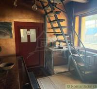 Innenraum eines Einfamilienhauses mit Metalltreppe und Holztisch, helle Wände.