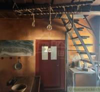 Innenraum eines Einfamilienhauses mit Holztreppe, rustikalem Tisch und künstlerischem Wandgemälde.