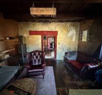 Rustikales Wohnzimmer in einem Einfamilienhaus mit Ledersesseln und einem Boden in Holzoptik.