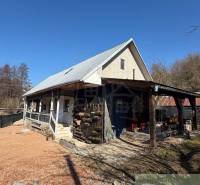 Ein Einfamilienhaus in Ratkovské Bystré mit einem Satteldach und einer Holzveranda.