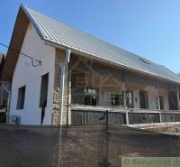 Ein Einfamilienhaus in Ratkovské Bystré mit Garten, weißer Fassade und Metalldach.