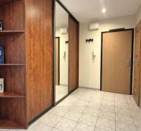 Eingangsflur in einer Zweizimmerwohnung mit Fliesenboden und Bücherregalen.