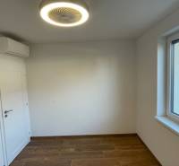 Ein Raum in einem Einfamilienhaus mit einem Boden in Holzoptik, Klimaanlage und Fenster.