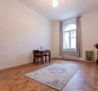 Ein Zimmer in einer 3-Zimmer-Wohnung mit einem Holzboden, einem Tisch und einer Pflanze.