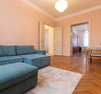 Ein Zimmer in einer 3-Zimmer-Wohnung mit einem blauen Sofa, einem Holzboden-Dekor und einem Essbereich.