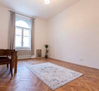 Ein Zimmer in einer 3-Zimmer-Wohnung mit einem Boden in Holzoptik, einem Teppich und einem Tisch.