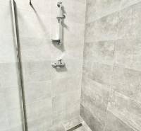 Duschkabine mit modernen Fliesen und Edelstahlzubehör im Büro.