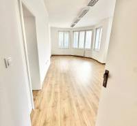 Helle Büros mit Holzboden und großen Fenstern.