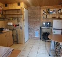 Eine Küche in einer Hütte mit Holzdekor und einem gemauerten Kamin, ausgestattet mit grundlegenden Möbeln.