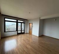 Ein Zimmer in einem Einfamilienhaus mit einem Boden in Holzoptik und großen Fenstern zum Garten.