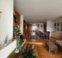 Wohnzimmer in einem Einfamilienhaus mit Holzboden, Esstisch und einem Kreuz an der Wand.