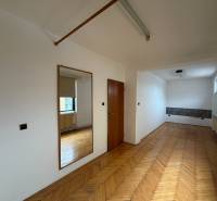 Ein Zimmer in einem Einfamilienhaus mit einem Boden in Holzoptik, einem Spiegel und einem Fenster.