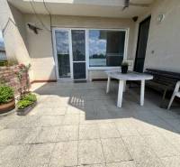 Die Terrasse des Einfamilienhauses in der Tálová-Straße in Veľké Orvište mit einem Plastiktisch und Blumen.
