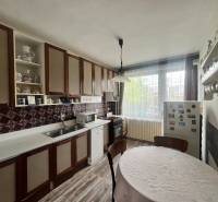 Eine Küche in einem Einfamilienhaus mit Holzschränken, einem runden Tisch und einem Boden mit Holzdekor.