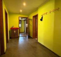 Flur mit Kleiderhaken und gelben Wänden, Holzboden in einem Einfamilienhaus.