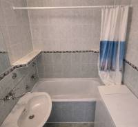 Badezimmer mit Badewanne und Waschbecken in einer 2-Zimmer-Wohnung, geflieste Wände.