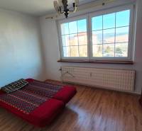 Schlafzimmer mit Bett, Schrank und Boden mit Holzdekor in einer 2-Zimmer-Wohnung.