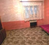 Ein Zimmer in einem Einfamilienhaus mit Teppich, Bett und Schrank, Vorhang am Fenster.