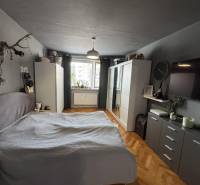 Schlafzimmer in einer 3-Zimmer-Wohnung mit Schrank, Bett und Boden in Holzoptik.