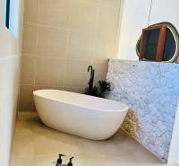 Ein Badezimmer in einem Einfamilienhaus mit freistehender Badewanne und Steinverkleidung an der Wand.