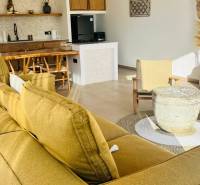 Innenraum eines Einfamilienhauses mit Sofa, Küche, Rattanstühlen und Accessoires aus natürlichen Materialien.